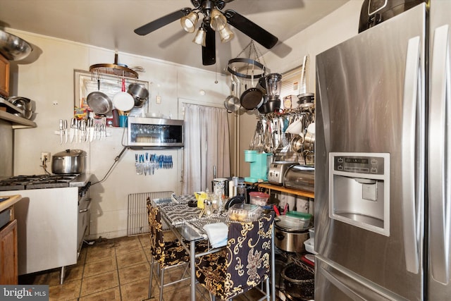 kitchen with stainless steel fridge, radiator heating unit, ceiling fan, and dark tile patterned flooring