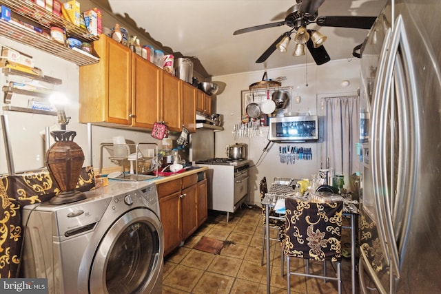 kitchen with dark tile patterned flooring, ceiling fan, stainless steel appliances, and washer / clothes dryer