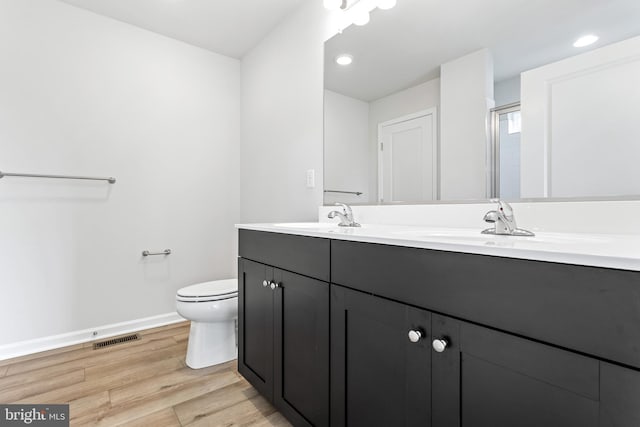 bathroom featuring toilet, hardwood / wood-style floors, and dual bowl vanity