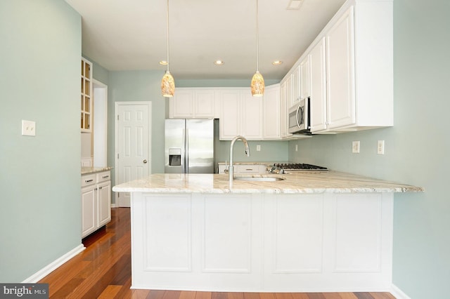 kitchen featuring kitchen peninsula, appliances with stainless steel finishes, decorative light fixtures, light stone counters, and white cabinetry