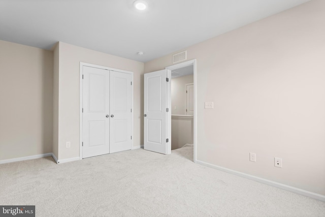 unfurnished bedroom featuring a closet and light colored carpet