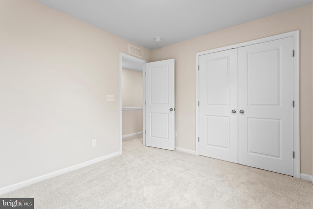 unfurnished bedroom with light carpet and a closet