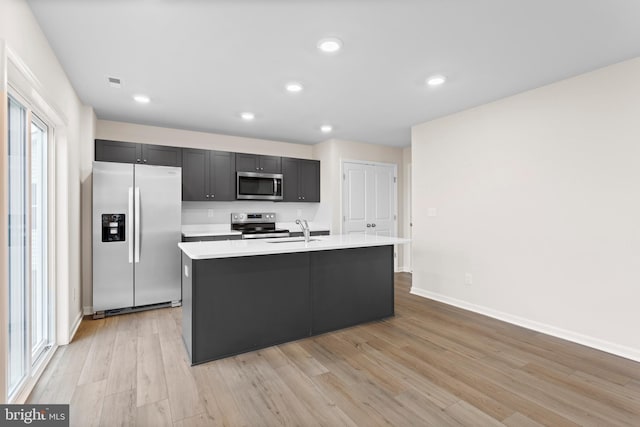 kitchen with sink, appliances with stainless steel finishes, a center island with sink, and light hardwood / wood-style floors