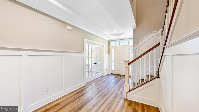 entryway featuring wainscoting, light wood-style flooring, stairway, a decorative wall, and recessed lighting