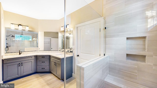 bathroom with a sink, a tile shower, and double vanity