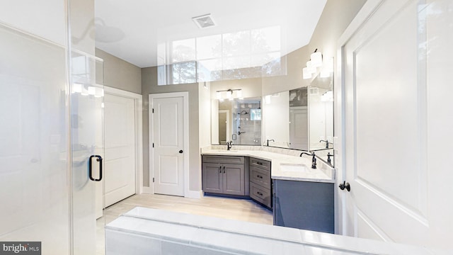 full bathroom with wood finished floors, a stall shower, vanity, and visible vents