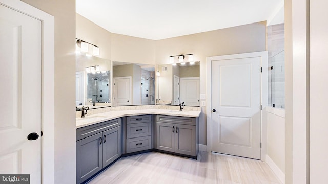 bathroom with double vanity, a stall shower, and a sink