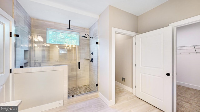 full bathroom featuring baseboards, a walk in closet, and a shower stall