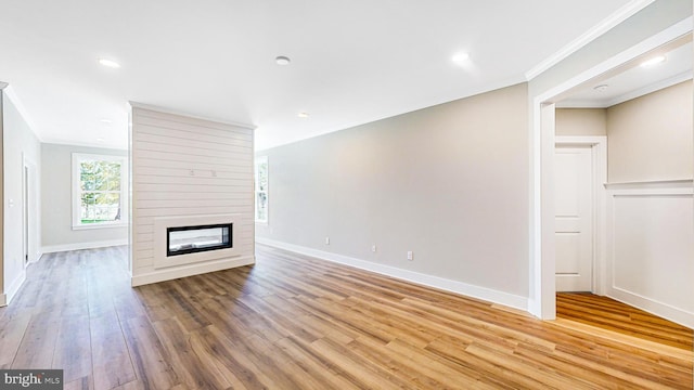 unfurnished living room featuring crown molding, a fireplace, recessed lighting, light wood-style flooring, and baseboards