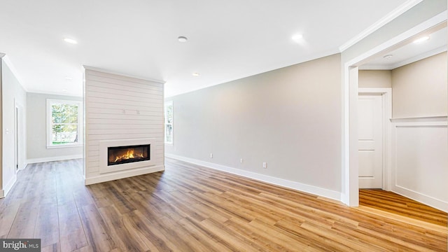 unfurnished living room with crown molding, a fireplace, light wood finished floors, recessed lighting, and baseboards