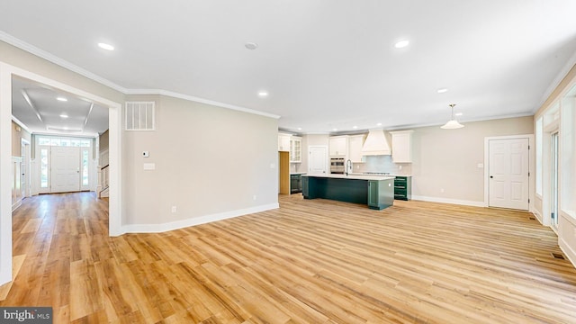 unfurnished living room featuring ornamental molding, visible vents, light wood finished floors, and stairs