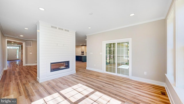 unfurnished living room featuring a large fireplace, light wood-style floors, plenty of natural light, and crown molding