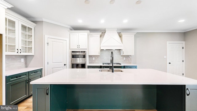 kitchen featuring custom exhaust hood, stainless steel appliances, light countertops, glass insert cabinets, and white cabinetry