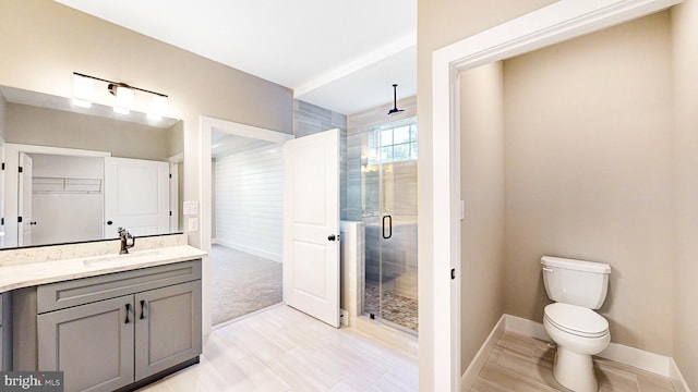 bathroom with toilet, vanity, baseboards, a stall shower, and a walk in closet