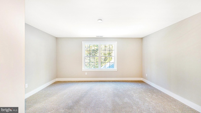 carpeted spare room with visible vents and baseboards