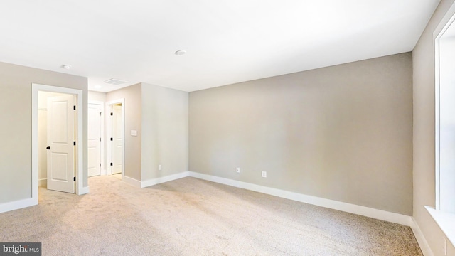 unfurnished room with light carpet, visible vents, and baseboards