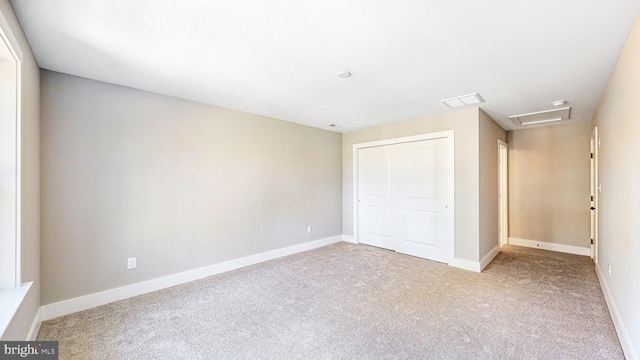 unfurnished bedroom featuring attic access, baseboards, and a closet