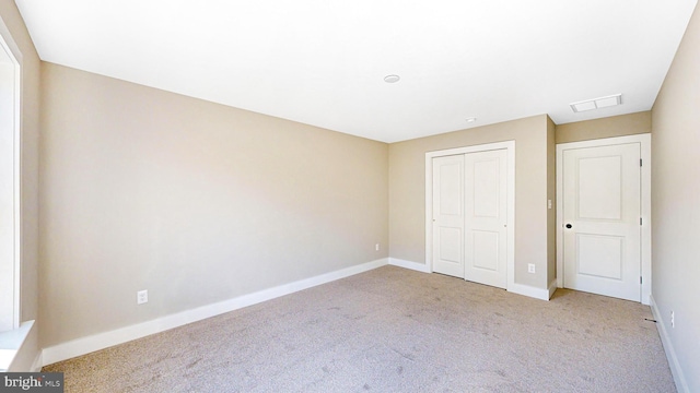 unfurnished bedroom with light carpet, visible vents, baseboards, and a closet