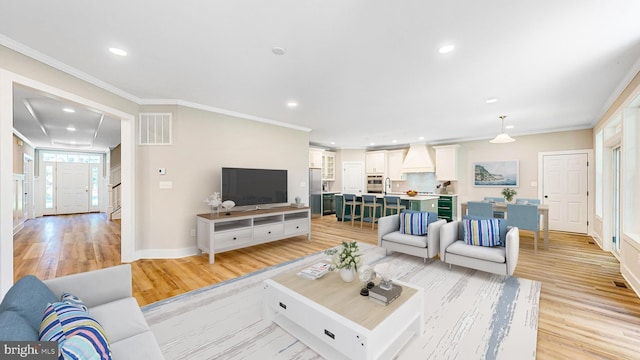 living room featuring light wood-style flooring, recessed lighting, visible vents, and crown molding