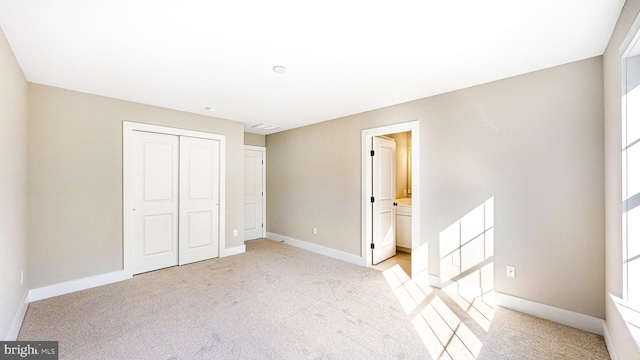 unfurnished bedroom featuring a closet, light carpet, and baseboards