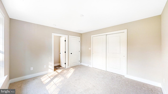 unfurnished bedroom featuring a closet, light colored carpet, and baseboards