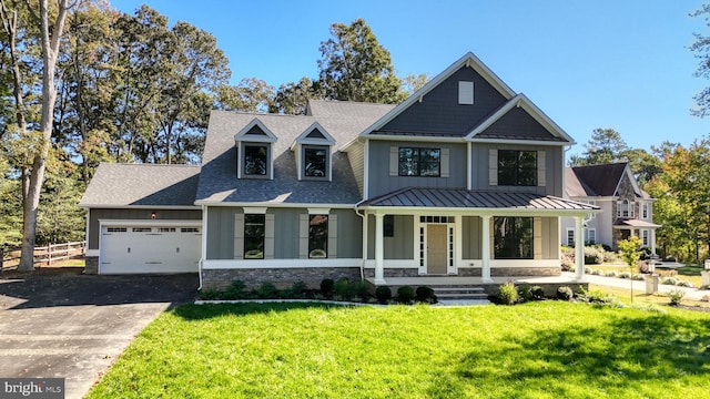 view of front facade with stone siding, metal roof, covered porch, a standing seam roof, and a front lawn