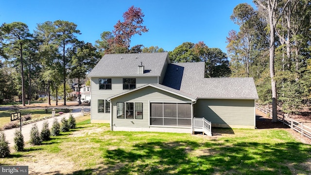 back of property with a shingled roof, a lawn, and a sunroom