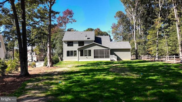 rear view of house with a sunroom, fence, and a yard