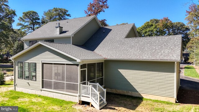 rear view of property featuring a sunroom and a shingled roof