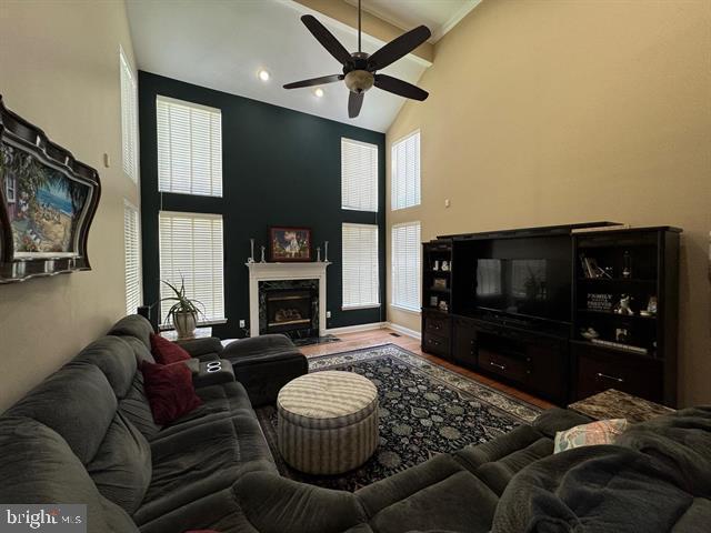 living room featuring ceiling fan, wood-type flooring, a fireplace, and high vaulted ceiling