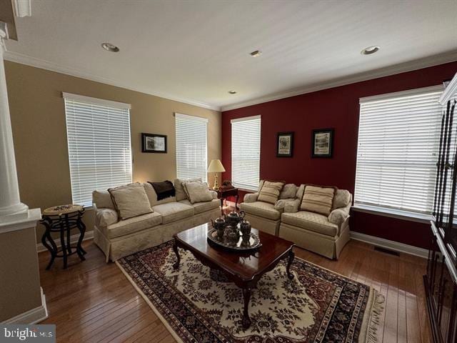 living room with dark hardwood / wood-style floors, crown molding, and decorative columns