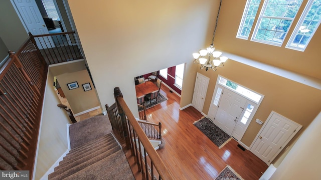 foyer featuring wood-type flooring, a towering ceiling, and a notable chandelier