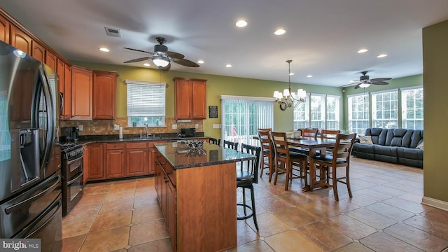 kitchen featuring sink, decorative light fixtures, fridge with ice dispenser, a kitchen island, and a breakfast bar area