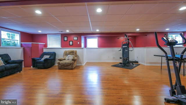 workout area with a paneled ceiling and wood-type flooring