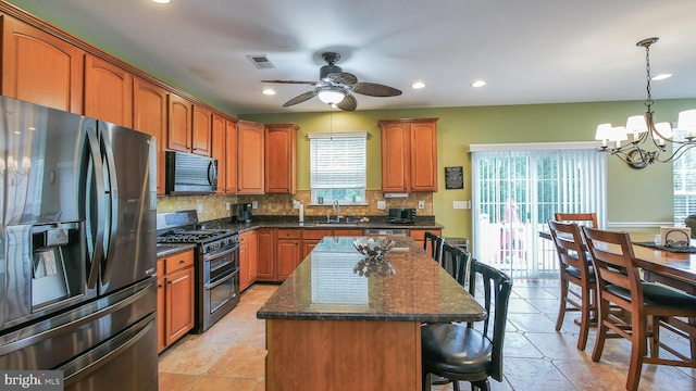 kitchen featuring ceiling fan with notable chandelier, sink, black appliances, a center island, and hanging light fixtures