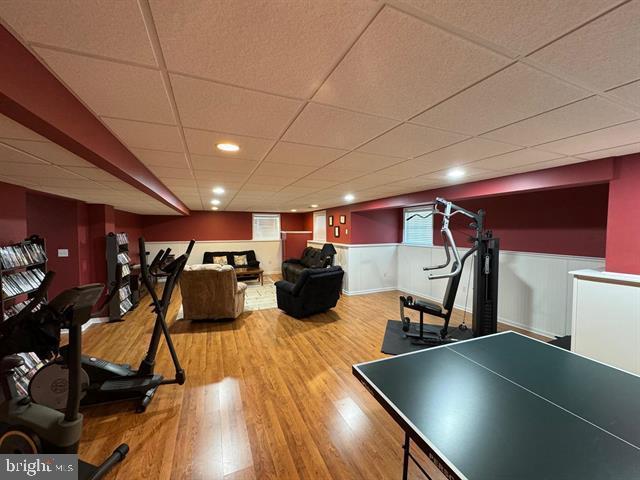 recreation room with a drop ceiling and hardwood / wood-style flooring