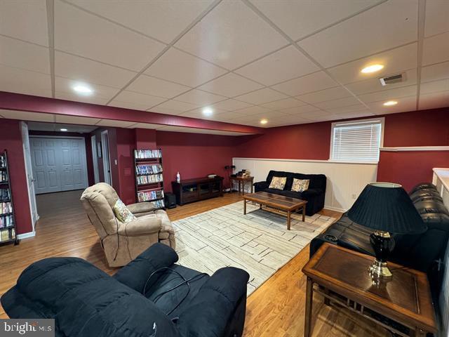 living room with hardwood / wood-style floors and a drop ceiling