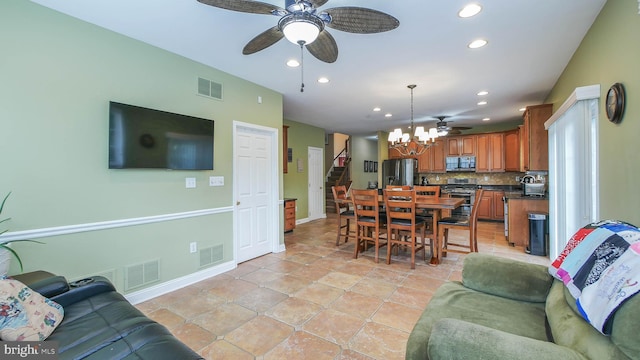 tiled living room featuring ceiling fan with notable chandelier