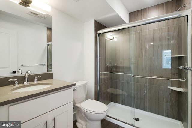 bathroom with a shower with shower door, toilet, and vanity