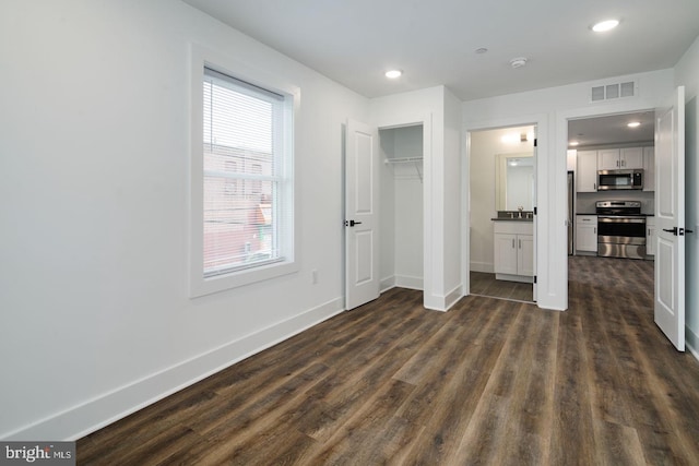 bedroom featuring dark wood-type flooring and ensuite bath