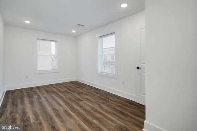 empty room featuring a healthy amount of sunlight and dark wood-type flooring