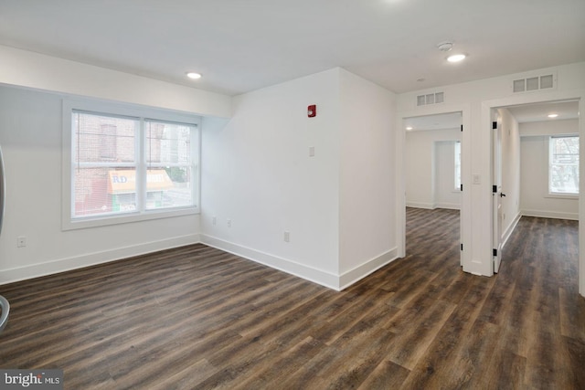 unfurnished room featuring a wealth of natural light and dark hardwood / wood-style floors