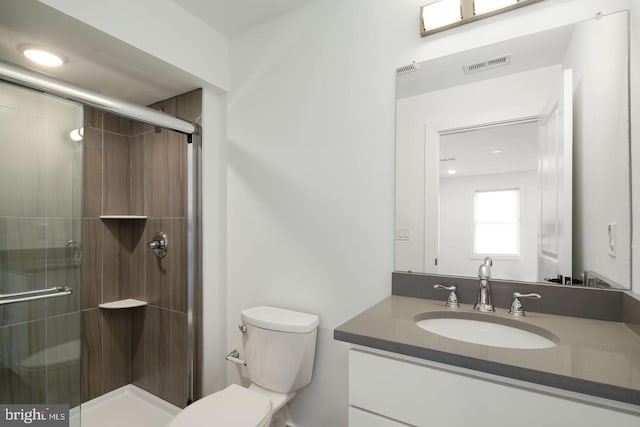 bathroom featuring vanity, toilet, and a shower with door