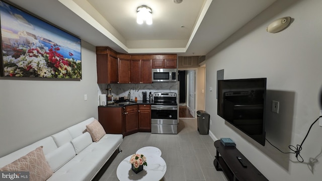 kitchen with stainless steel appliances, a raised ceiling, and tasteful backsplash