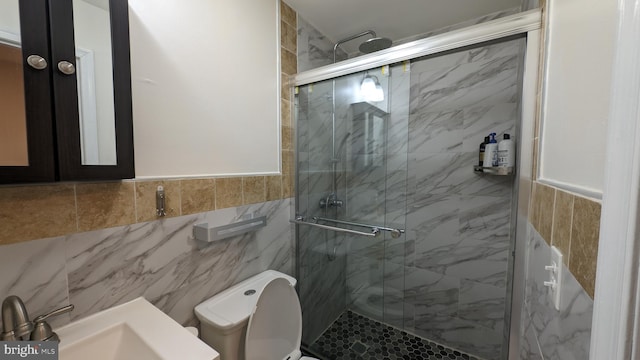 bathroom with toilet, tile walls, and a shower with shower door