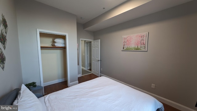 bedroom with dark hardwood / wood-style floors and a closet