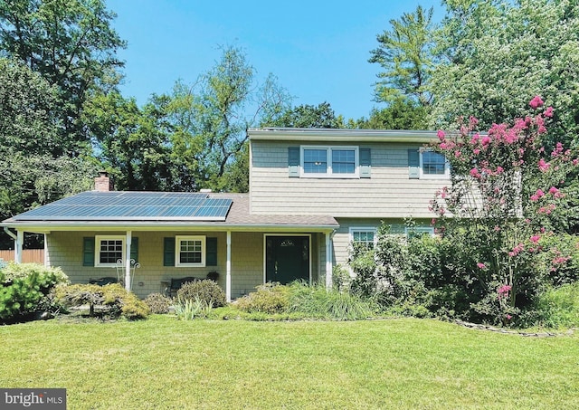 view of front of house featuring a front lawn, covered porch, and solar panels