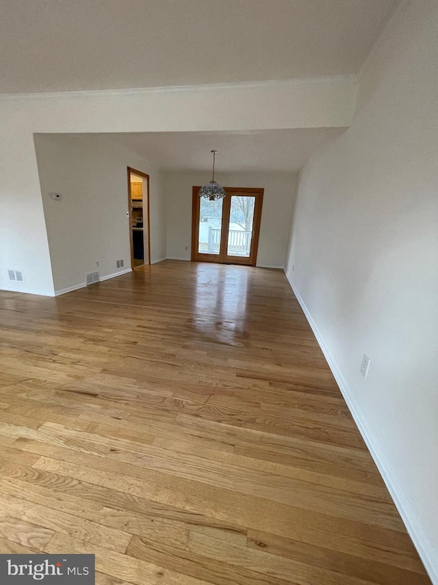 spare room with light wood-type flooring, french doors, and an inviting chandelier