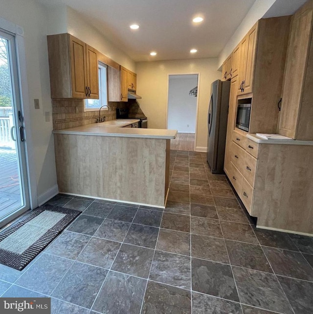 kitchen featuring kitchen peninsula, stainless steel fridge, tasteful backsplash, sink, and electric range