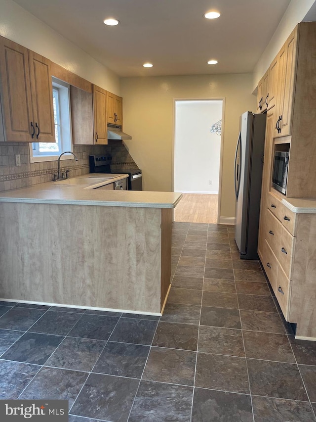 kitchen with backsplash, sink, kitchen peninsula, and stainless steel appliances